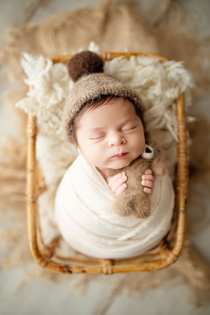 bebelus nou nascut cu jucarie plus intr-o fotografie studio